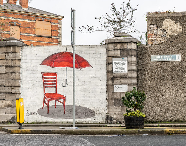 Picture of mural street art with empty red chair with floating red umbrella